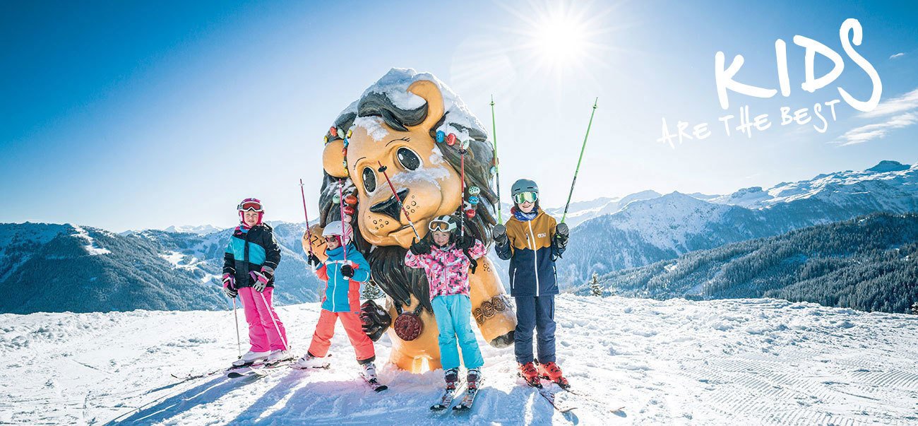 Kinder stehen vor einer übergroßen Lazy Luis Figur. Winterpanorama im Hintergrund.