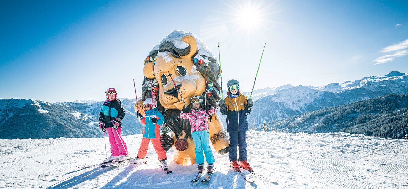 Kinder stehen vor einer übergroßen Lazy Luis Figur. Winterpanorama im Hintergrund.